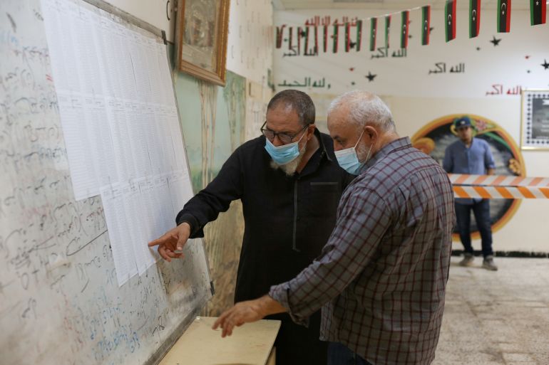 People check names to receive their voter cards inside a polling station in Tripoli, Libya