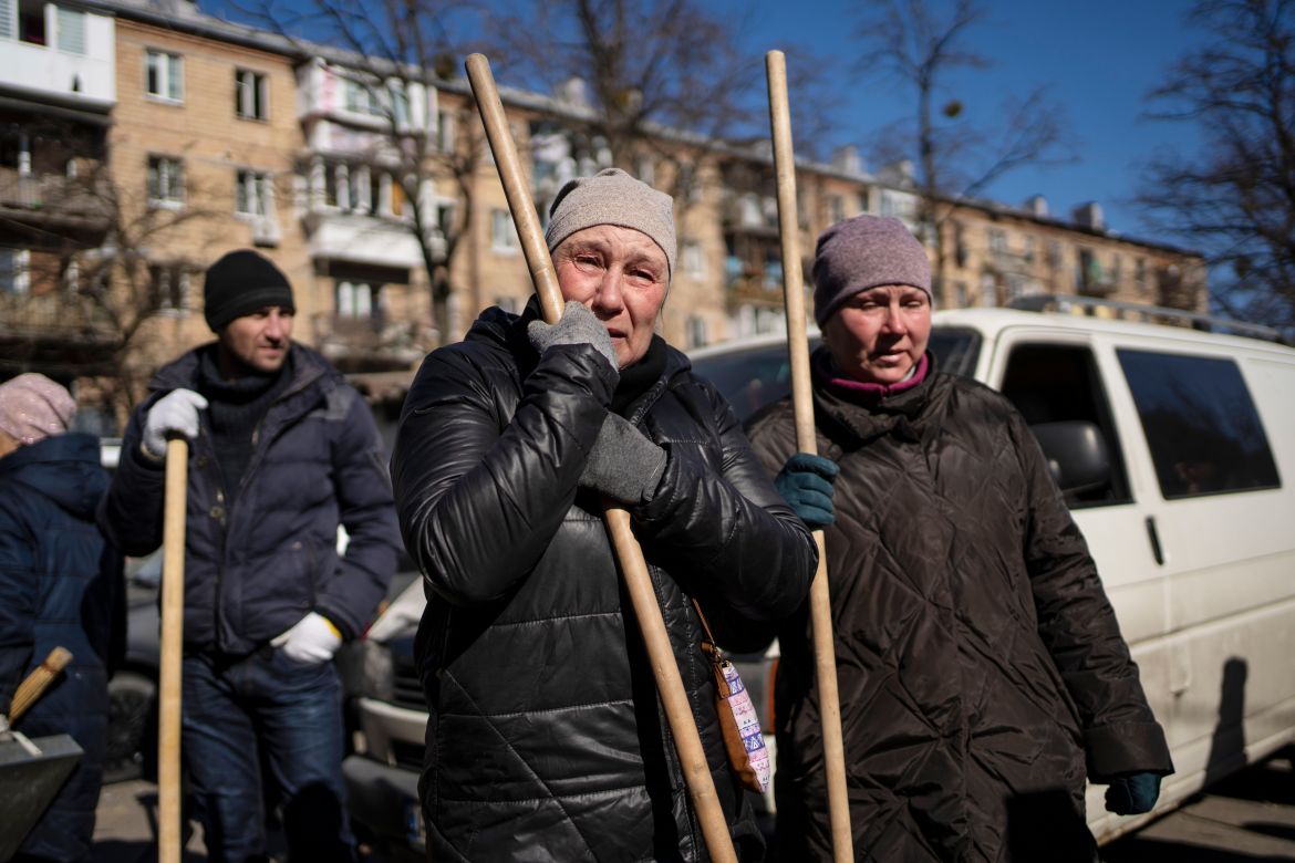A woman cries before starting to clean the site where a bombing damaged residential buildings in Kyiv