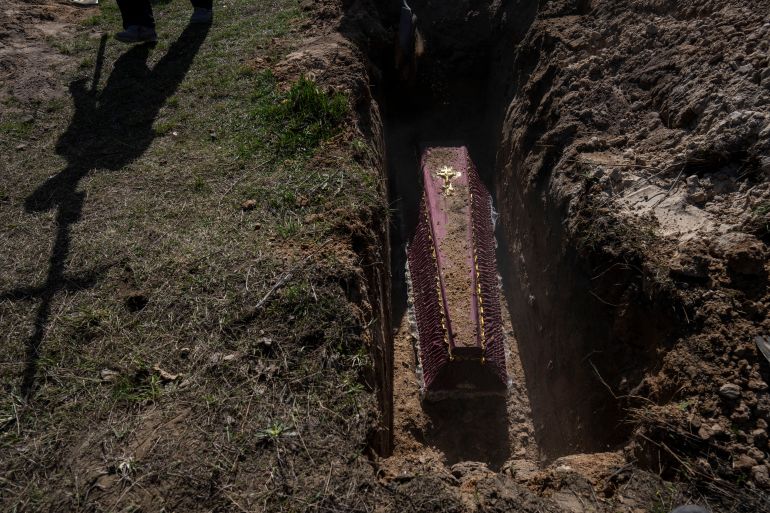 A cemetery worker carries a cross for the tomb of Tetyana Gramushnyak, 75, who was killed by shelling on March 19 while cooking food outside her home in Bucha