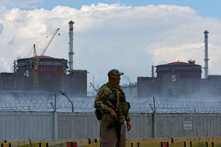 A serviceman with a Russian flag on his uniform stands guard near the Zaporizhzhia nuclear site