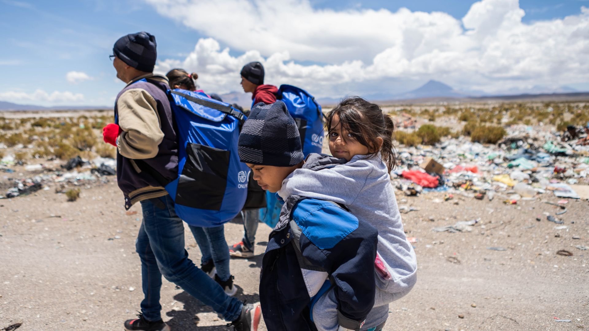 Allyson rides on the back of one of her siblings as her family makes its way across the Altiplano highlands