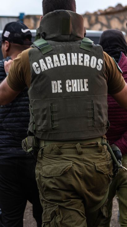 Law enforcement — wearing flak vests labelled "Carabineros de Chile" — make arrests along the border.