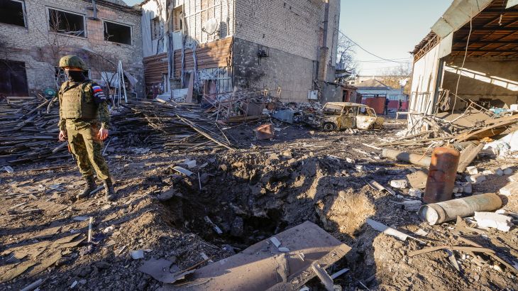 An investigator stands next to a crater in the site of recent shelling
