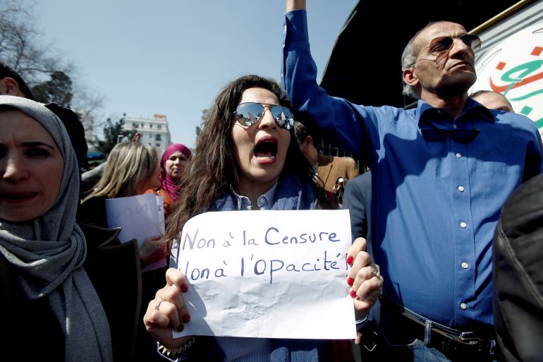 Journalists working at state media carry banners and shout slogans during a protest in front of the state TV building to demand freedom to cover mass protests against President Abdelaziz Bouteflika, in Algiers, Algeria