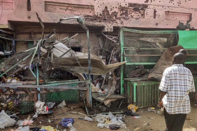 People walk past a medical centre building riddled with bullet holes at the Souk Sitta (Market Six) in the south of Khartoum on June 1, 2023.
