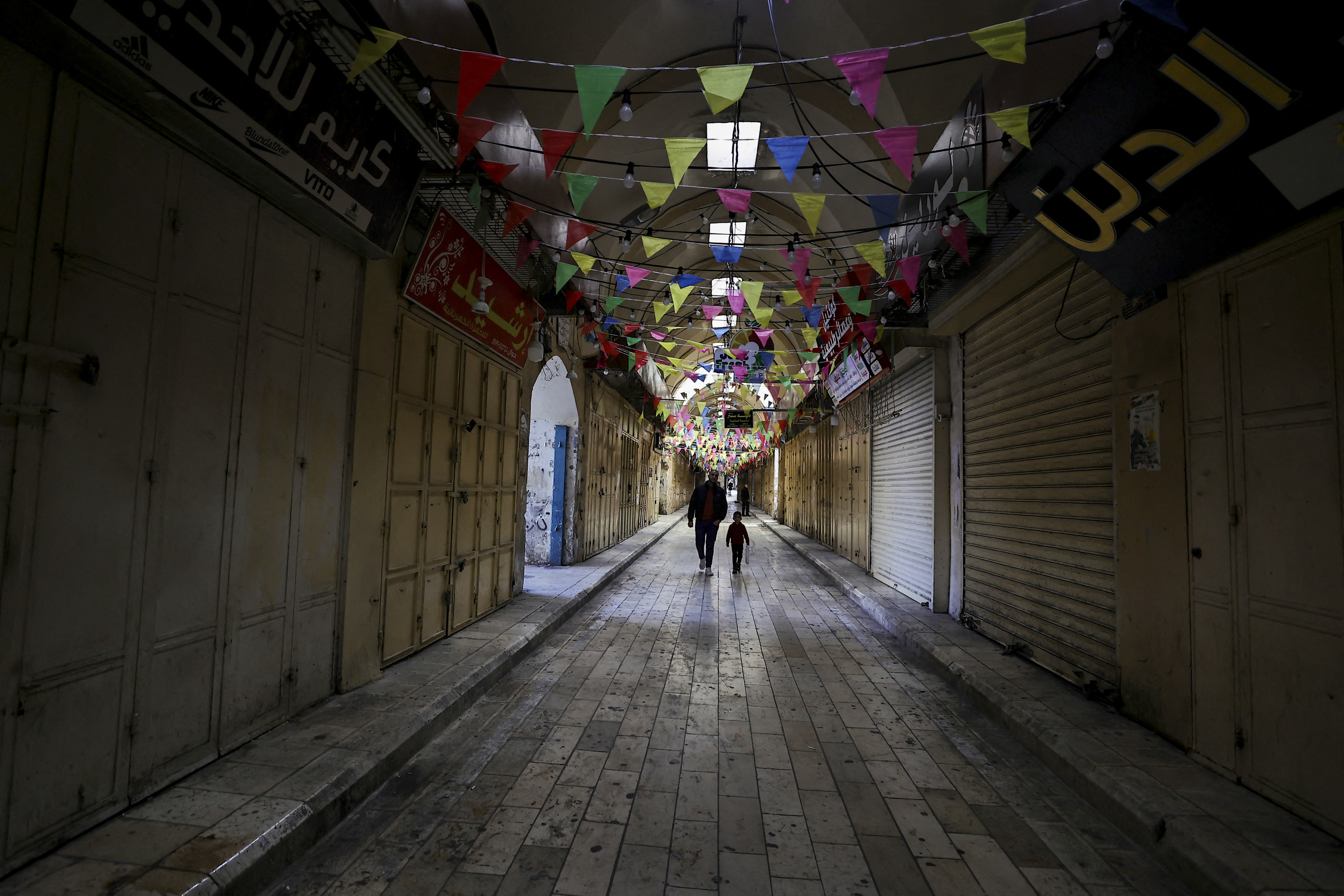 People walk past shuttered shops during a general strike in solidarity with Gaza in the occupied West Bank city of Nablus on December 11