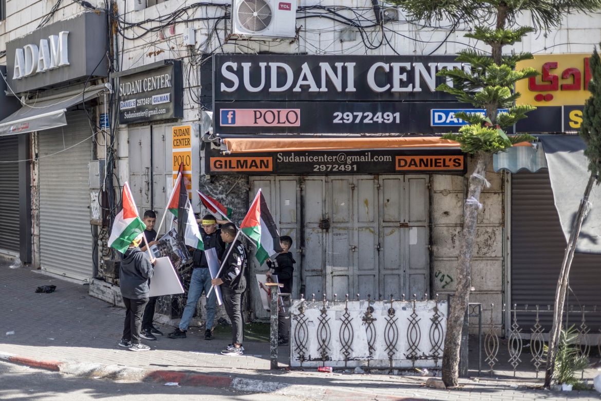 Palestinians lift national flags during a rally amid a general strike in Ramallah city in the occupied West Bank in solidarity with Gaza on December 11, 2023