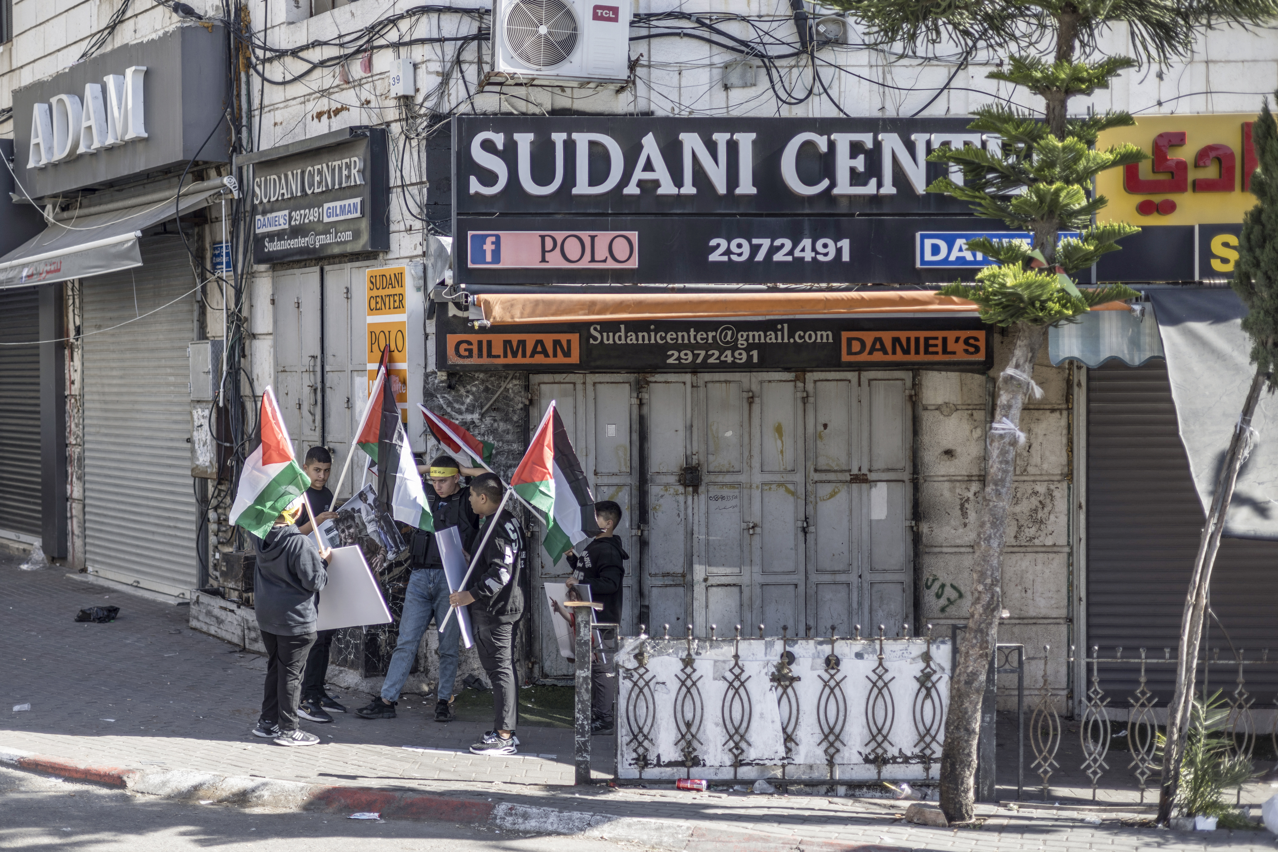 Palestinians lift national flags during a rally amid a general strike in Ramallah city in the occupied West Bank in solidarity with Gaza on December 11, 2023