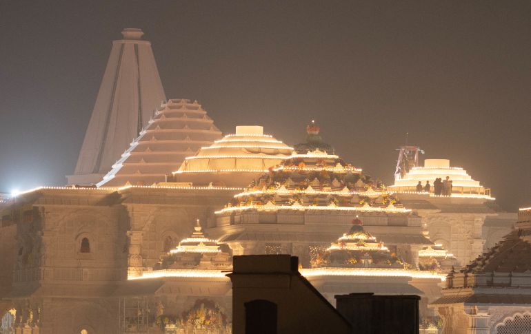 Labourers stand on top of the illuminated grand temple of Lord Ram ahead of its opening in Ayodhya in India, January 19, 2024. REUTERS/Adnan Abidi