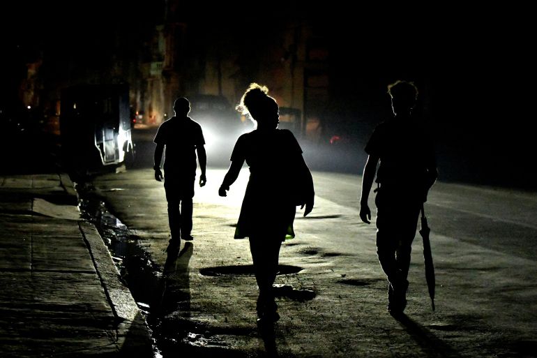 Three people walk down a darkened street during a blackout in Havana.