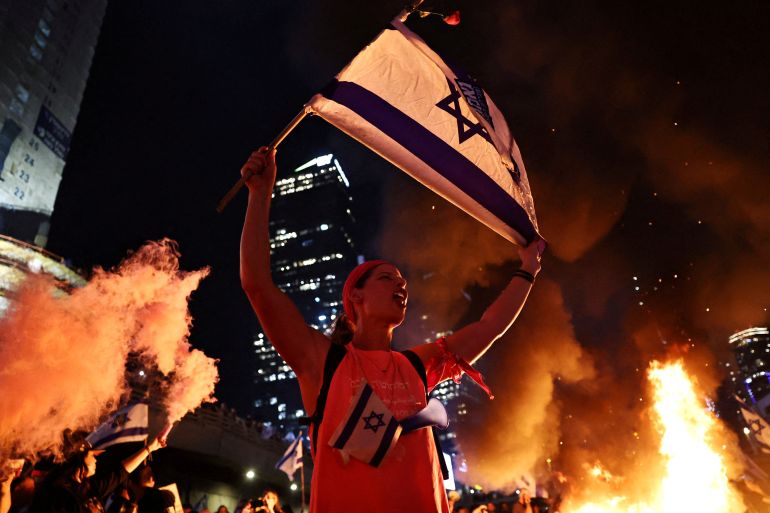 A person holds an Israeli flag as people demonstrate after Israeli Prime Minister Benjamin Netanyahu sacked his defense minister, Yoav Gallant, citing lack of trust, in Tel Aviv, Israel November 5, 2024. REUTERS/Thomas Peter TPX IMAGES OF THE DAY