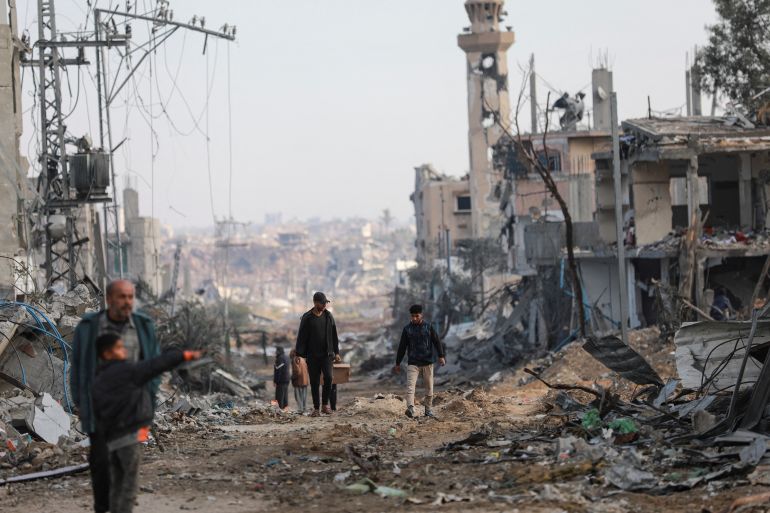 Palestinians walk next to damaged buildings after Israeli forces withdrew from a part of Nuseirat,
