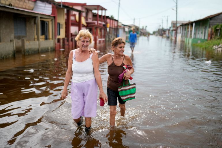 Women walking in flooded street in Cuba after Hurricane Rafael