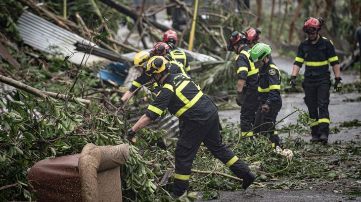 This photo provided on Monday Dec. 16, 2024 by the Civil Security shows rescue workers clearing a street in French territory of Mayotte in the Indian Ocean, after the island was battered by its worst cyclone in nearly a century. (UIISC7/Securite Civile via AP)