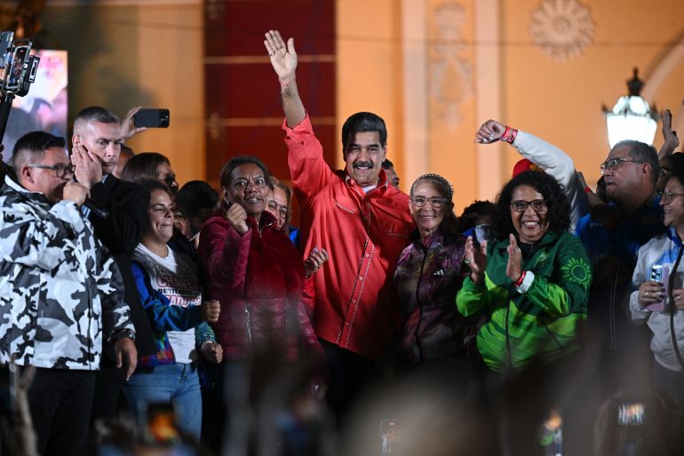 Venezuelan President Nicolas Maduro (C) waves to supporters next to his wife Cilia Flores (C-R) as he celebrates the results of the parliamentary and regional elections at the Bolivar square in Caracas on May 25, 2025. Low turnout predominated Sunday in Venezuela's gubernatorial and parliamentary elections after the opposition majority called for abstention in protest of President Nicolas Maduro's disputed re-election. (Photo by Federico PARRA / AFP)