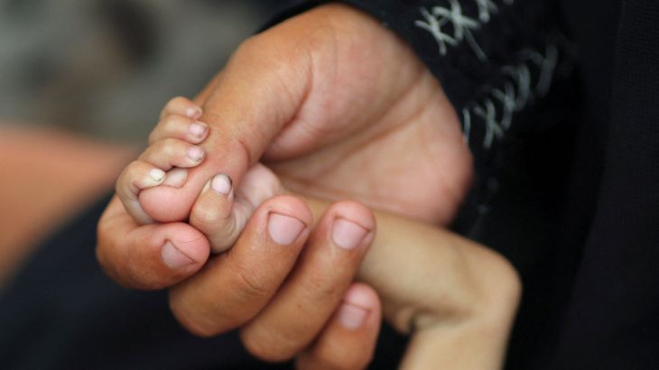 Palestinian mother Amira Muteir holds the hand of her five-month-old baby Ammar, whom she says is wasting away from malnutrition, in Gaza City, August 5, 2025. [Mahmoud Issa/Reuters]