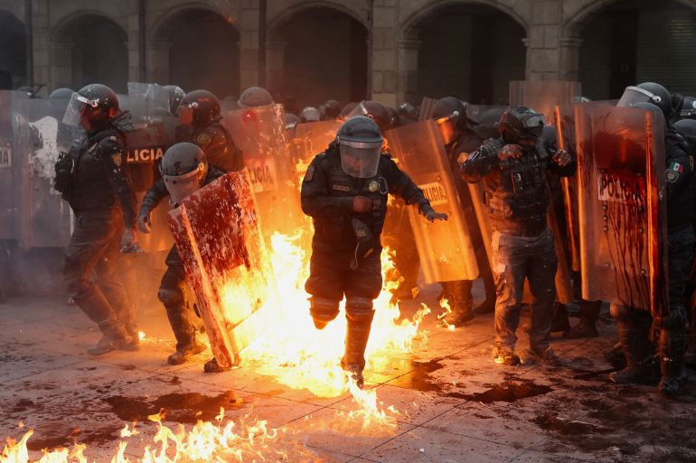 Police officers run away from flames as demonstrators clash with police officers during a march to mark the 57th anniversary of the 1968 Tlatelolco Square massacre, in which students were shot dead by the military, in Mexico City, Mexico