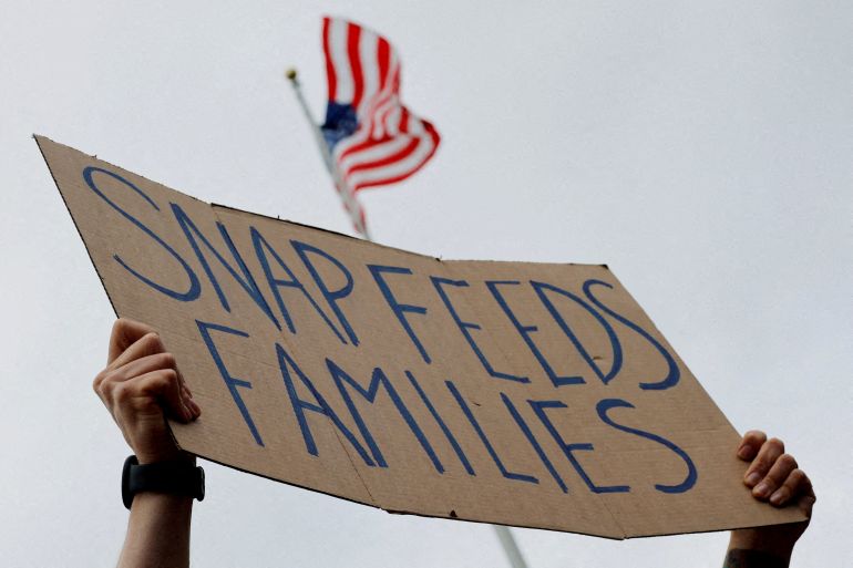 A man holds a sign reading "SNAP Feeds Families." [Brian Snyder/File Photo/Reuters]