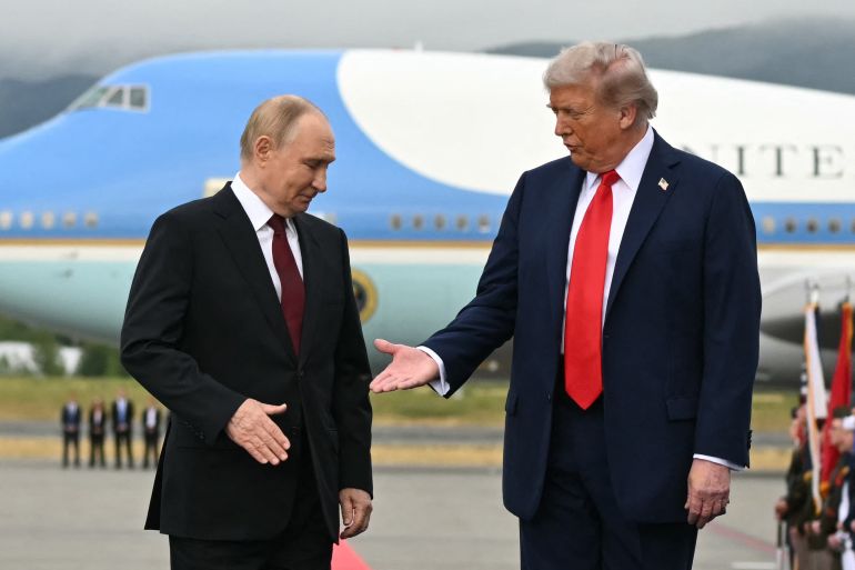 US President Donald Trump (R) reaches out to shake hands with Russian President Vladimir Putin as they pose on a podium on the tarmac after arrival at Joint Base Elmendorf-Richardson in Anchorage, Alaska, on August 15, 2025.