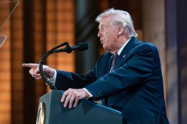 Donald Trump at a podium speaks and points